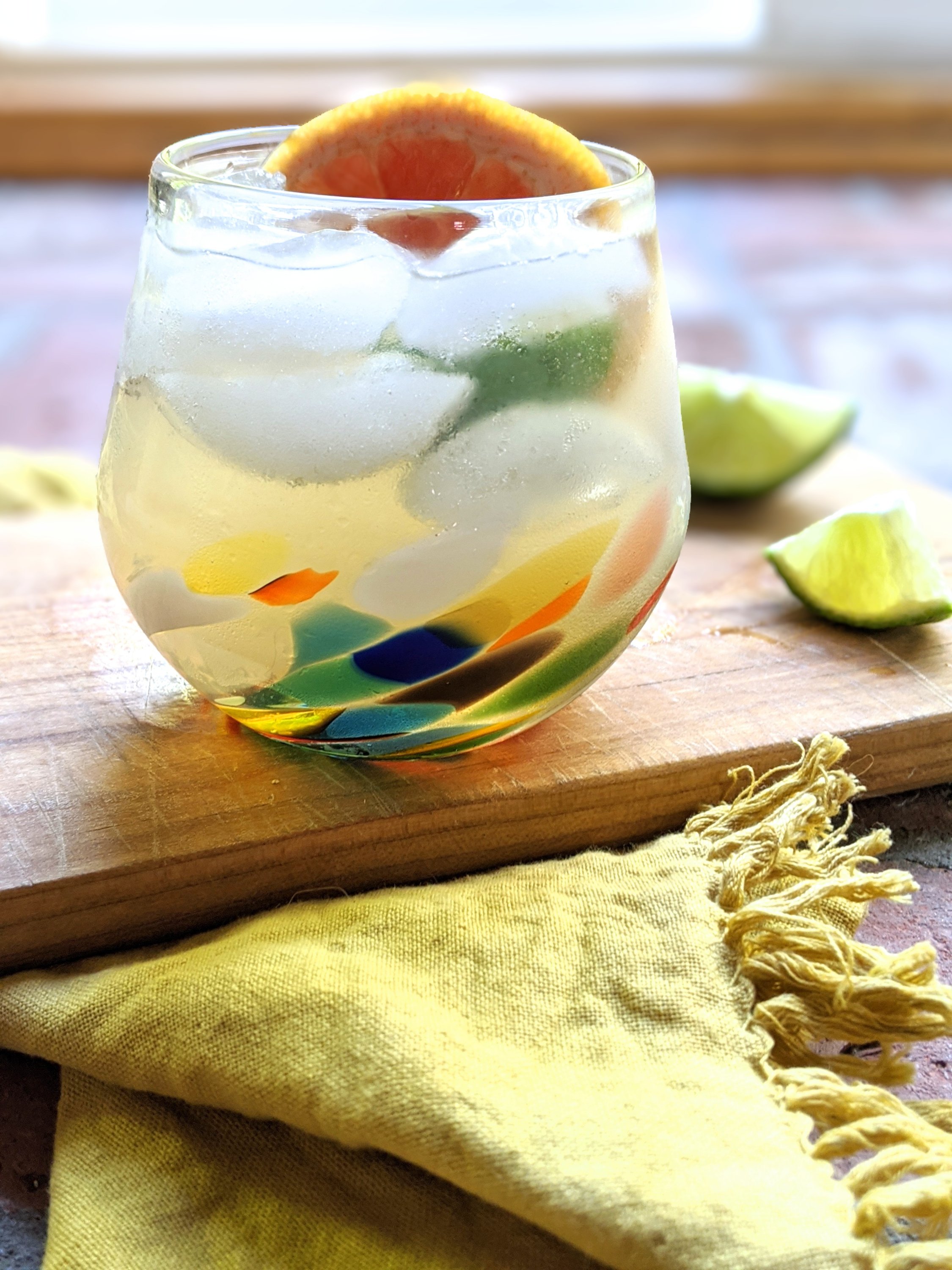 paloma with grapefruit tequila lime juice on a cutting board with lime wedges in the summertime