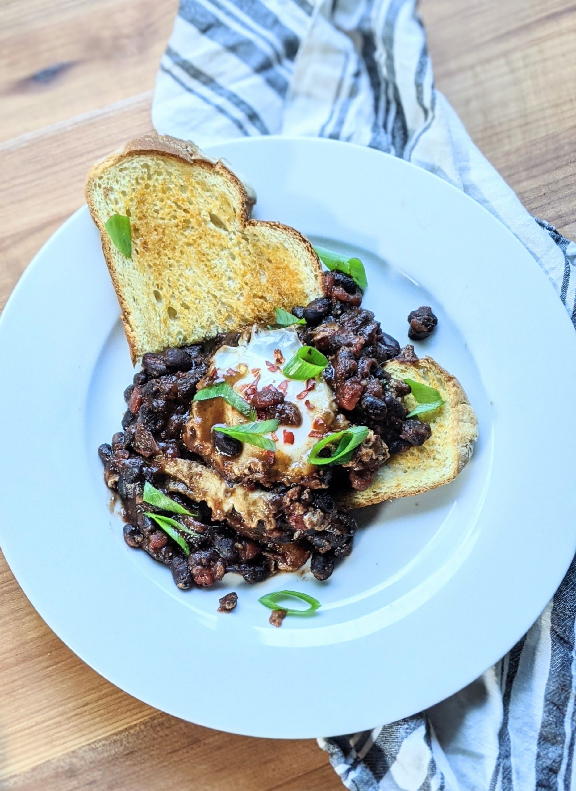 shakshuka with black beans on garlic toast with green onions tomatoes salsa verde eggs and beans breakfast and brunch recipes without gluten and meatless brunches mexican flavors