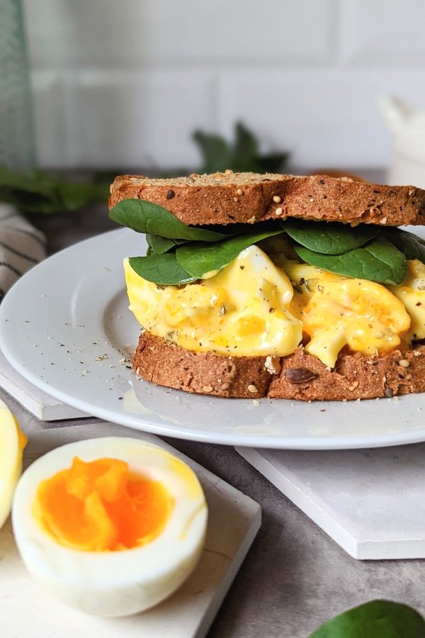 egg mayonnaise sandwich with spinach dill relish and gluten free or low carbohydrate bread on a plate with hardboiled eggs.