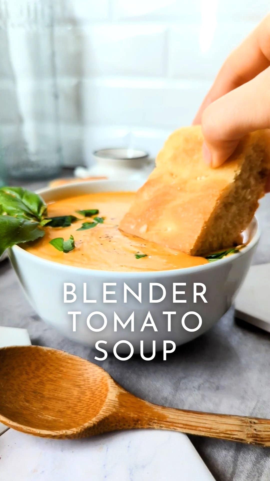 diced tomato soup in a blender creamy vegan cashew tomato soup recipe blended tomato soup creamiest vegan tomato soup recipe with bread and basil in a bowl.