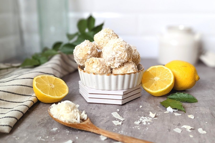 lemon energy bites recipe with shredded coconut balls recipe snacks healthy coconut recipes with shredded or flaked coconut in a dish with lemons and a wooden spoon on the table.