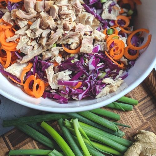 whole30 chinese chicken salad paleo recipes with asian dressing salad in a bowl with chopped green onions and fresh ginger root.
