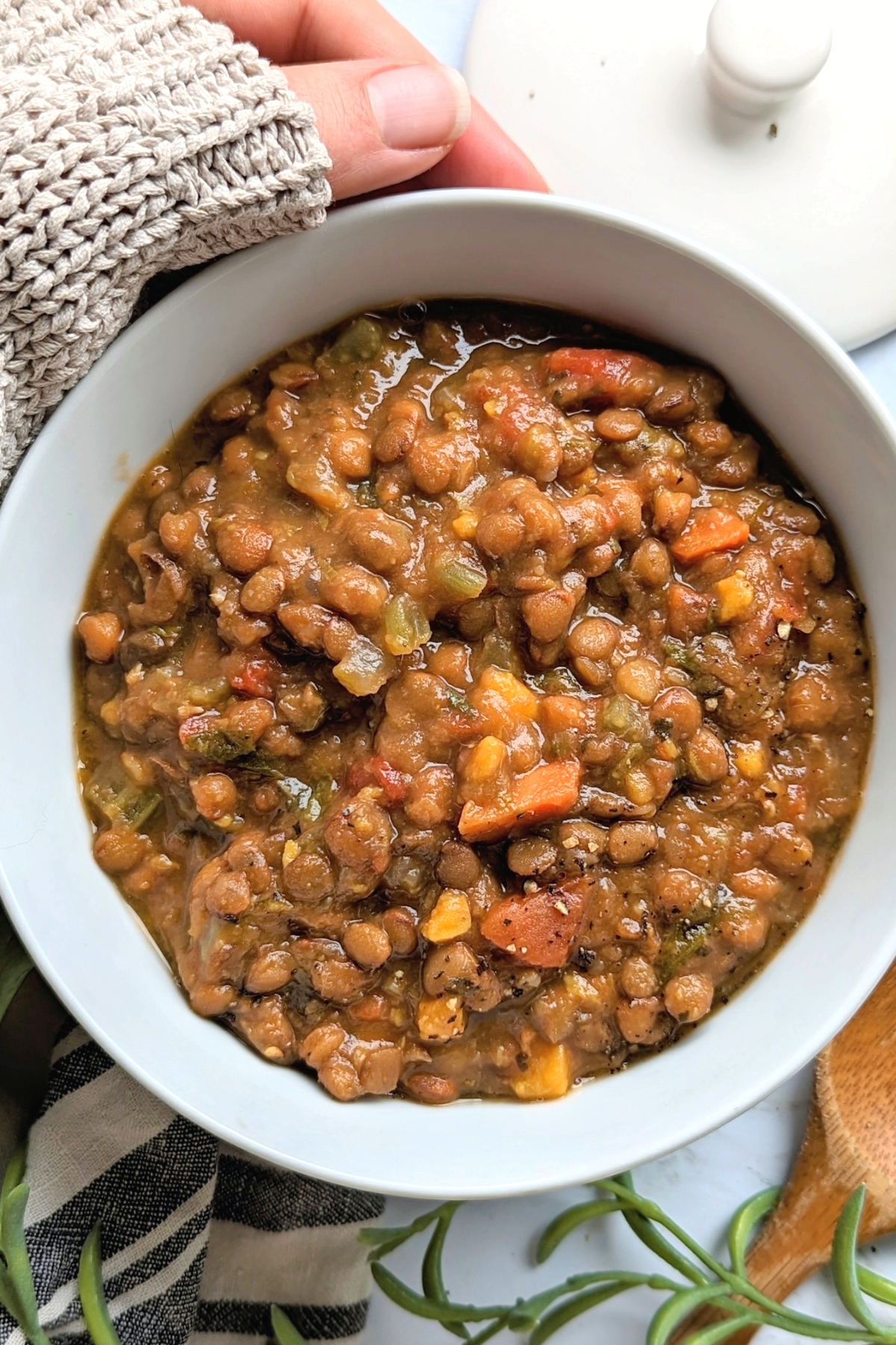 cozy lentil soup recipe sweater weather recipes with a hand holding a big bowl of lentil stew cooked in the instant pot pressure cooker
