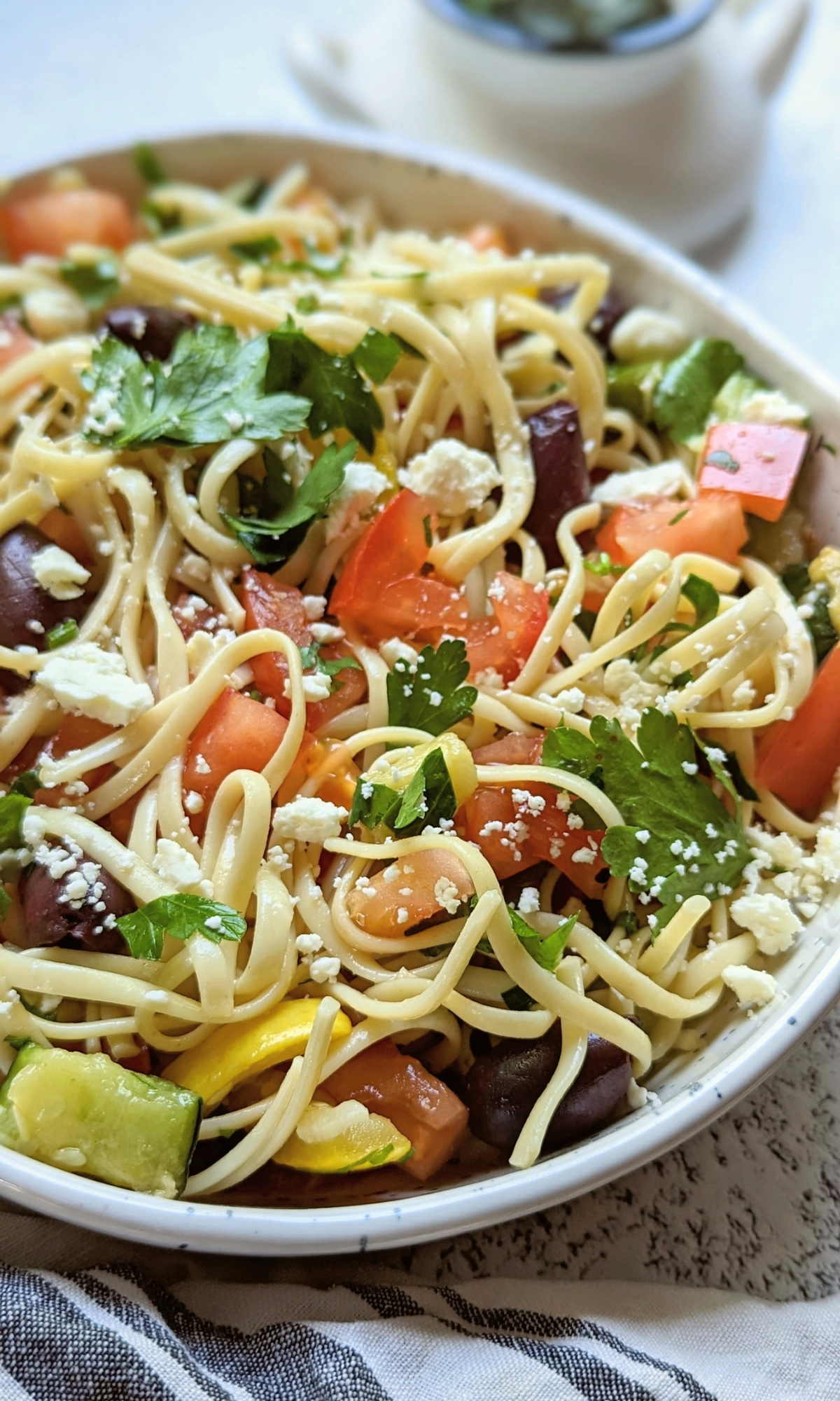 vegetable linguine noodle pasta salad recipe with tomatoes cucumber bell peppers parsley feta cheese olives in a red wine vinegar salad dressing.