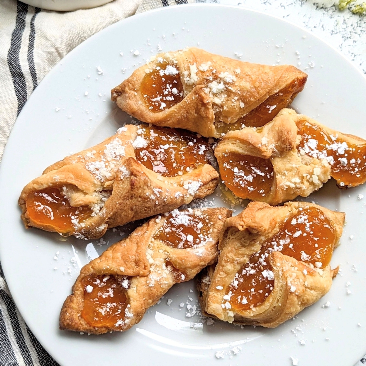 how to make kolachy cookies with apricot jam with powdered sugar on a plate with a striped French napkin