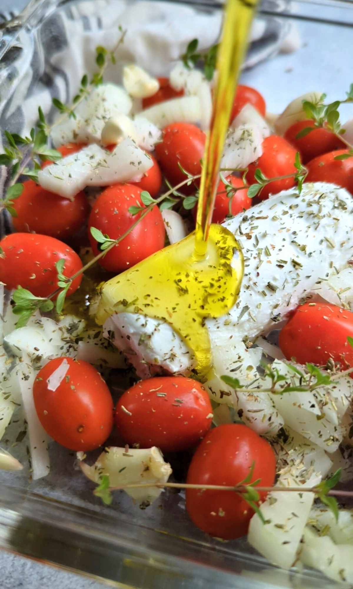 goat cheese drizzled with olive oil and tomatoes and fresh thyme in a baking dish tiktok goat cheese pasta recipe