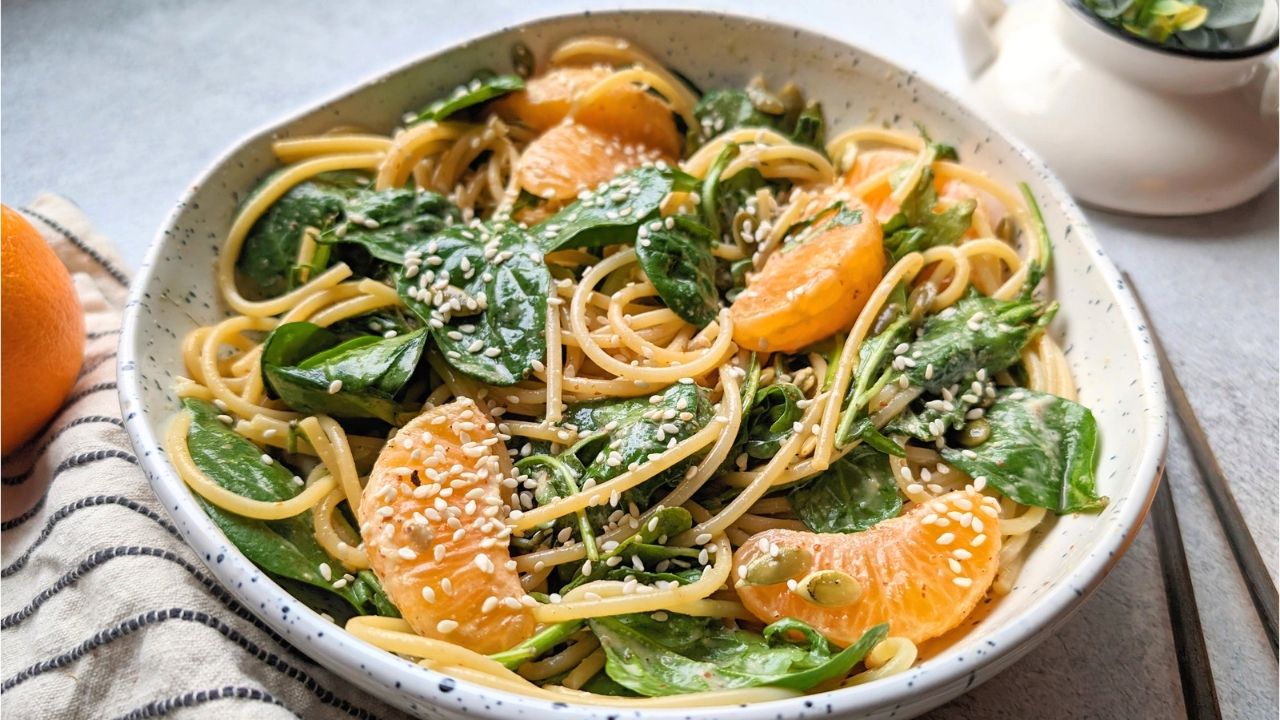 orange pasta salad recipe with noodles mandarin oranges baby spinach and a tangy homemade dressing in a bowl