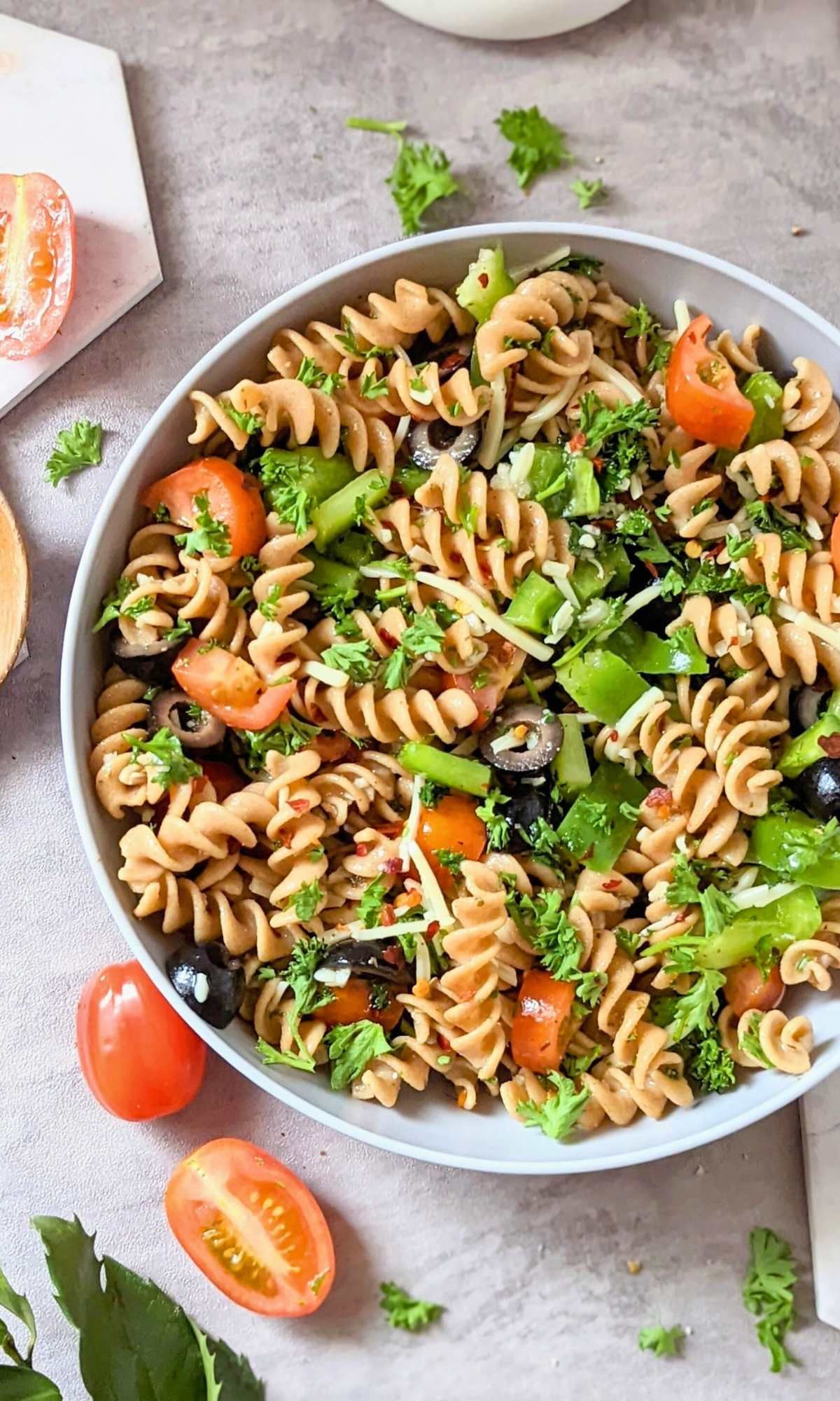 whole wheat rotini recipes in a bowl with sliced cherry tomatoes black olives italian dressing and parmesan cheese