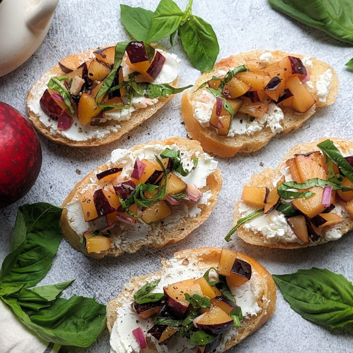 plum bruschetta with goat cheese and honey on toasted baguette slices with fresh basil