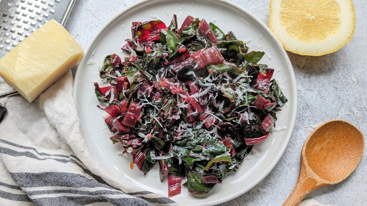 a plateful of red chard with green leaves and fresh parmesan cheese and lemon