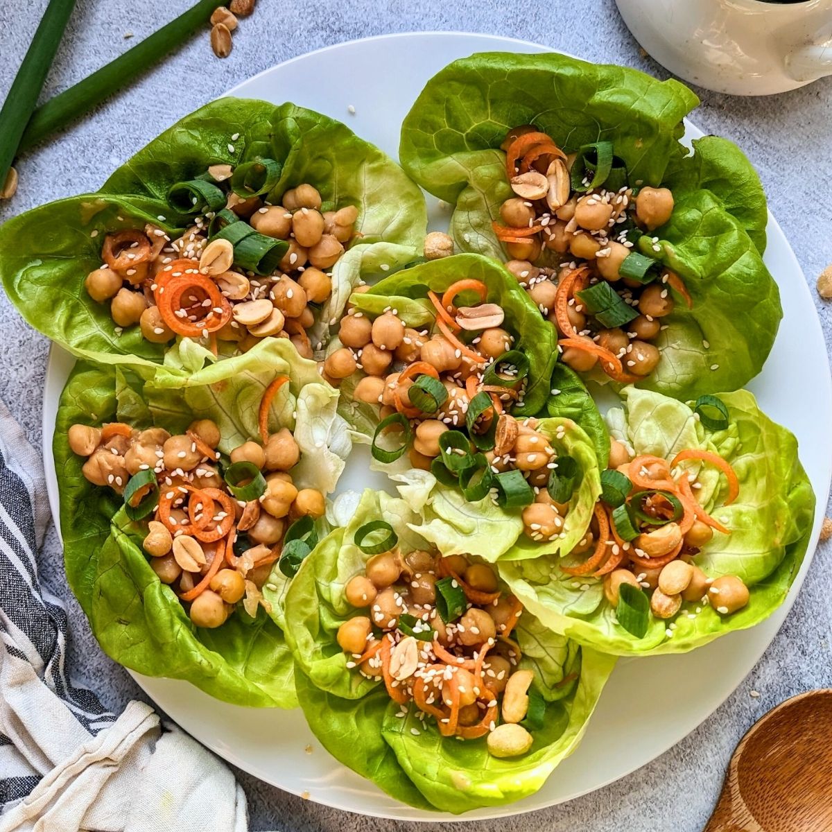 vegan lettuce wraps with chickpeas in butter lettuce cups with a spicy peanut sauce and topped with sesame seeds and green onions