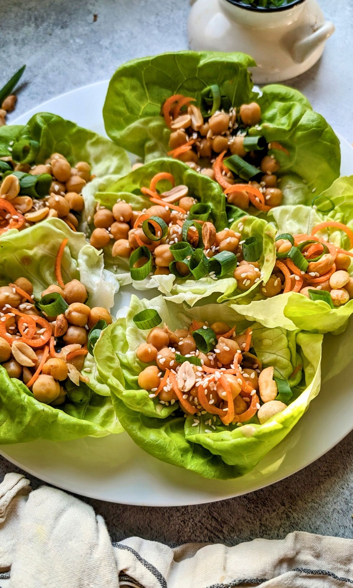 bibb lettuce cups filled with vegan chickpea and peanut filling with an asian peanut sauce on a plate