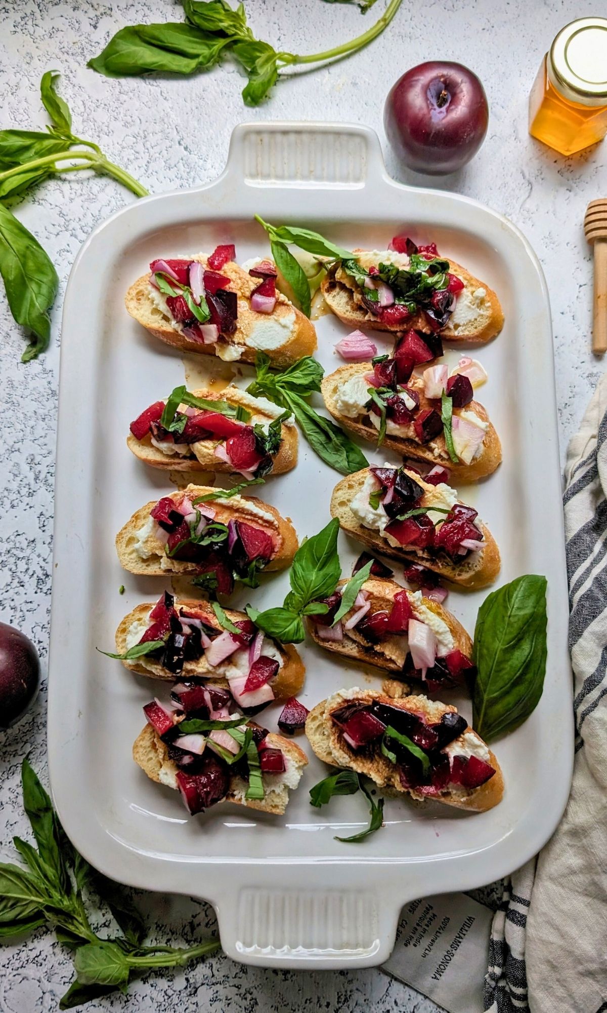plum bruschetta toasts with fresh basil honey and balsamic vinegar on a platter ready for a summer party.