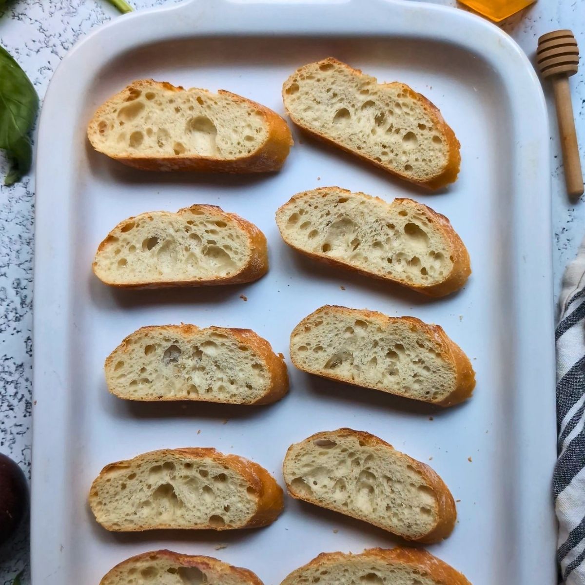 a tray of french baguettes sliced thin and lightly toasted in the oven.