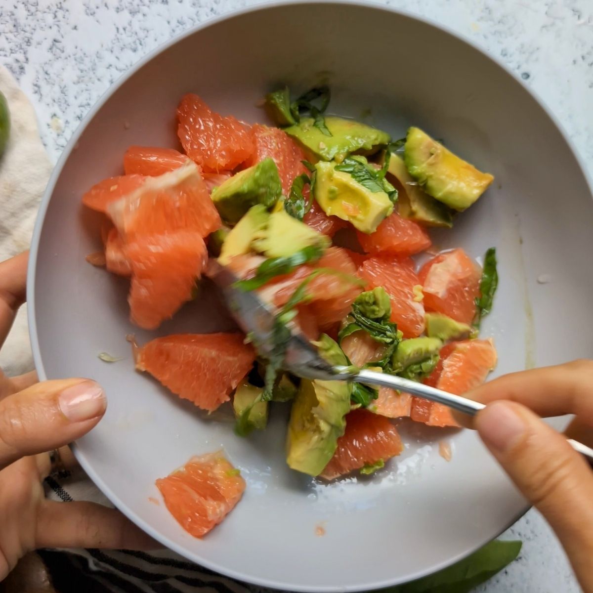 a spoon mixing the fresh avocado salad in a bowl with the lime juice.