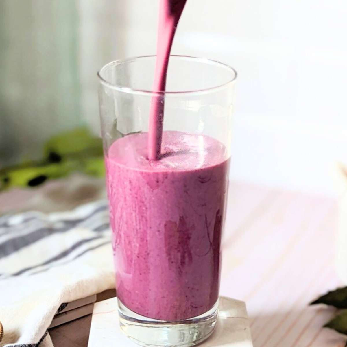 blueberry oatmeal smoothie being poured into a large glass from a vitamix blender.