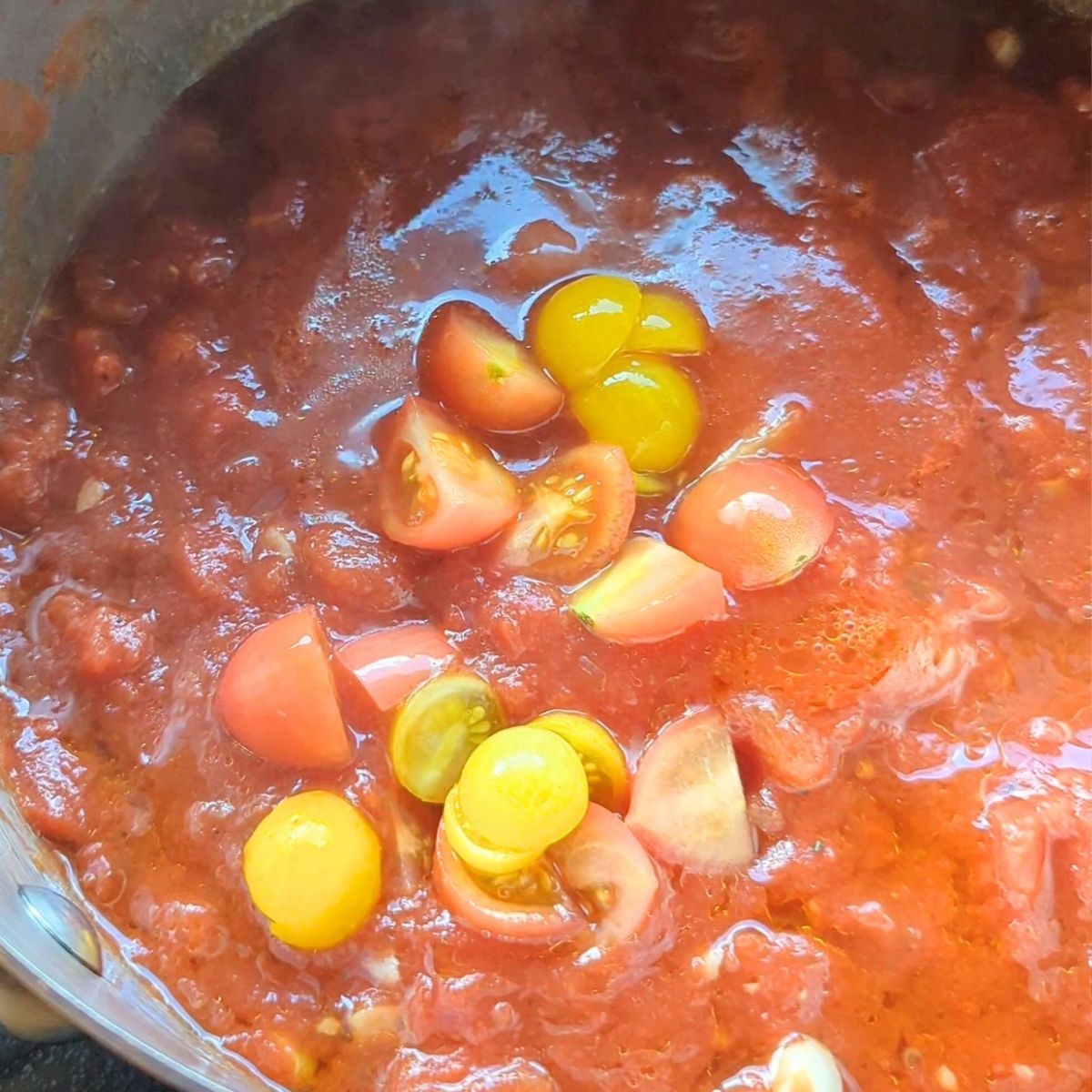 canned and fresh tomatoes in a pot with olive oil and garlic for pomodoro sauce.