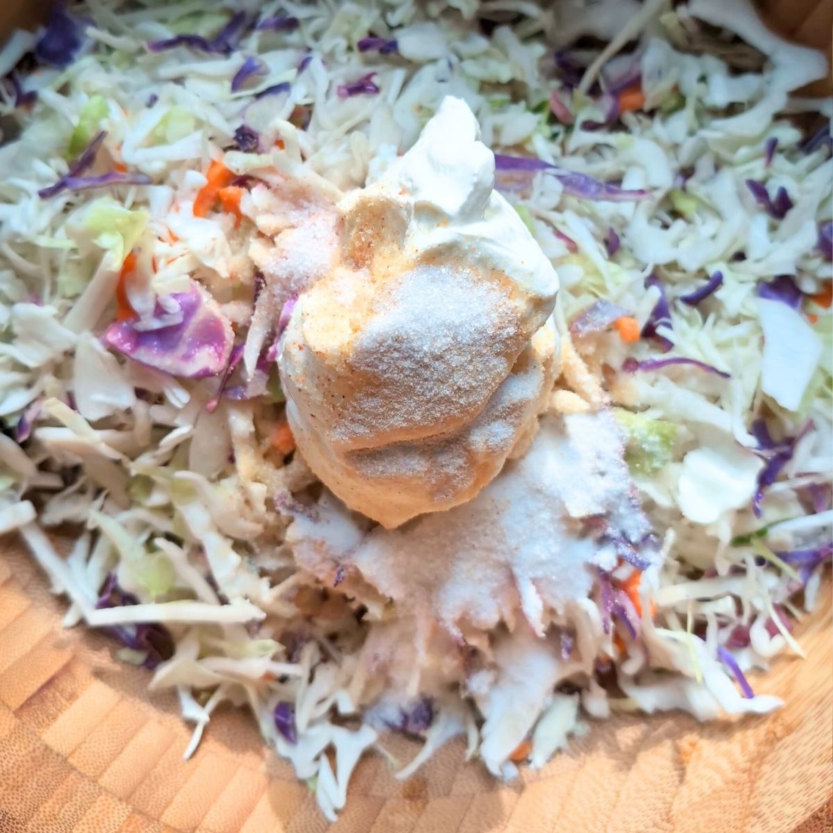 a bowl of coleslaw mix with sour cream spices and sugar.
