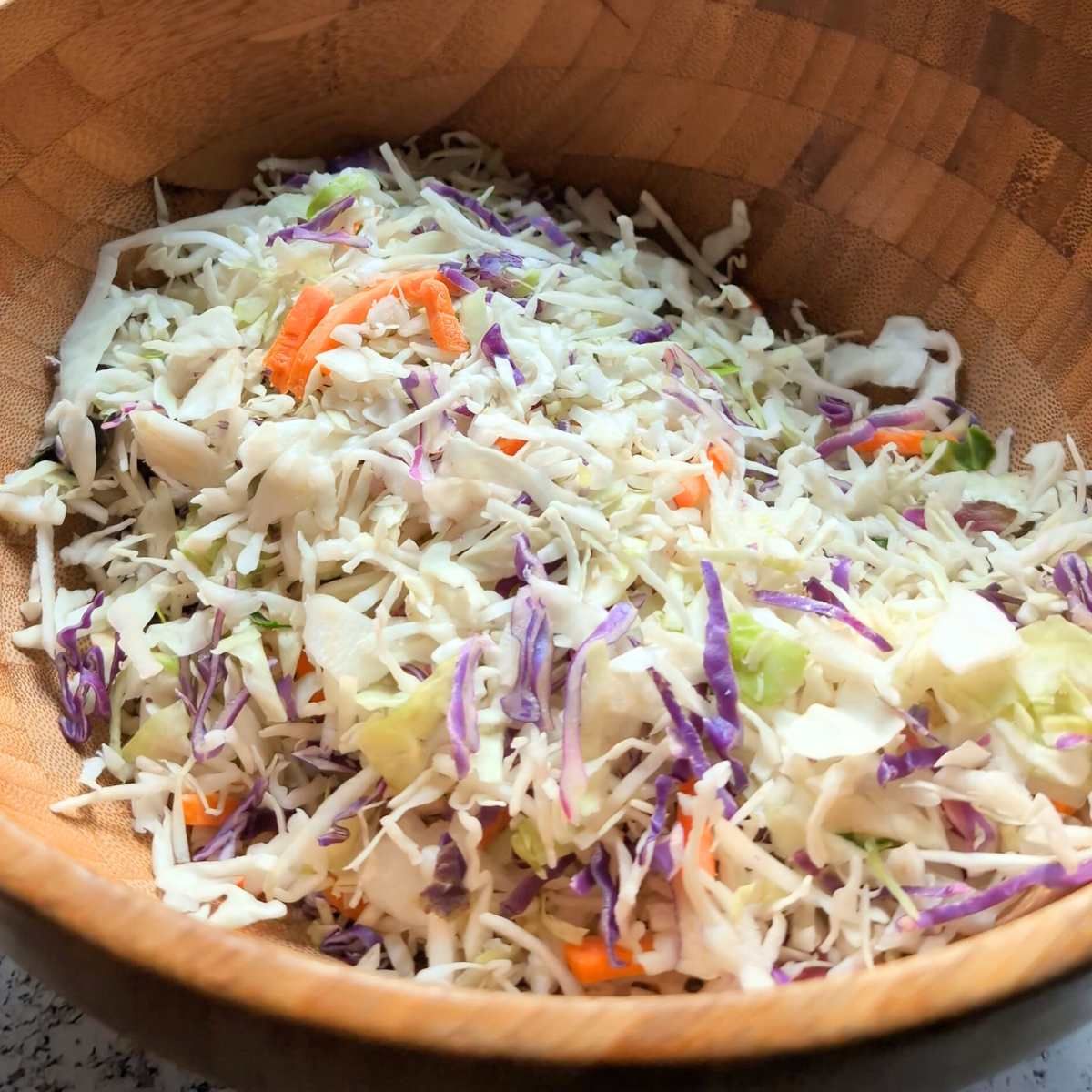 a wooden serving bowl full of coleslaw mix.