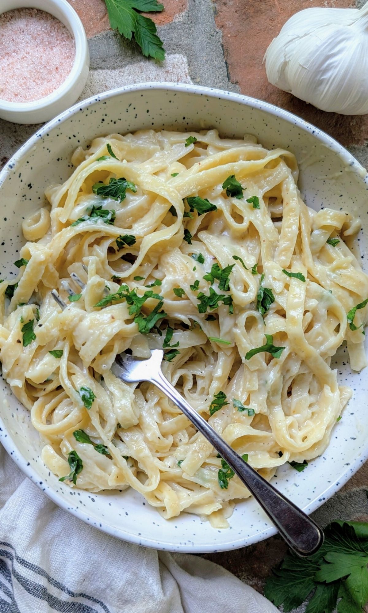 a fork twirling creamy oat milk pasta sauce topped with a fresh parsley garnish.