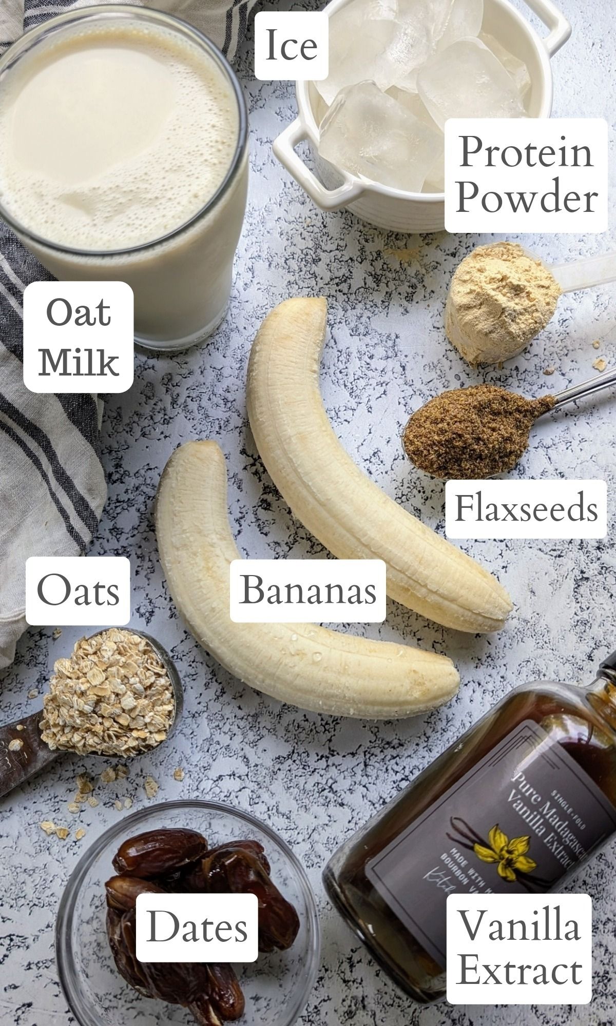 ingredients laid out for this oat milk smoothie with banana vanilla extract oats flaxseeds and plant-based milk and dates for sweetness.