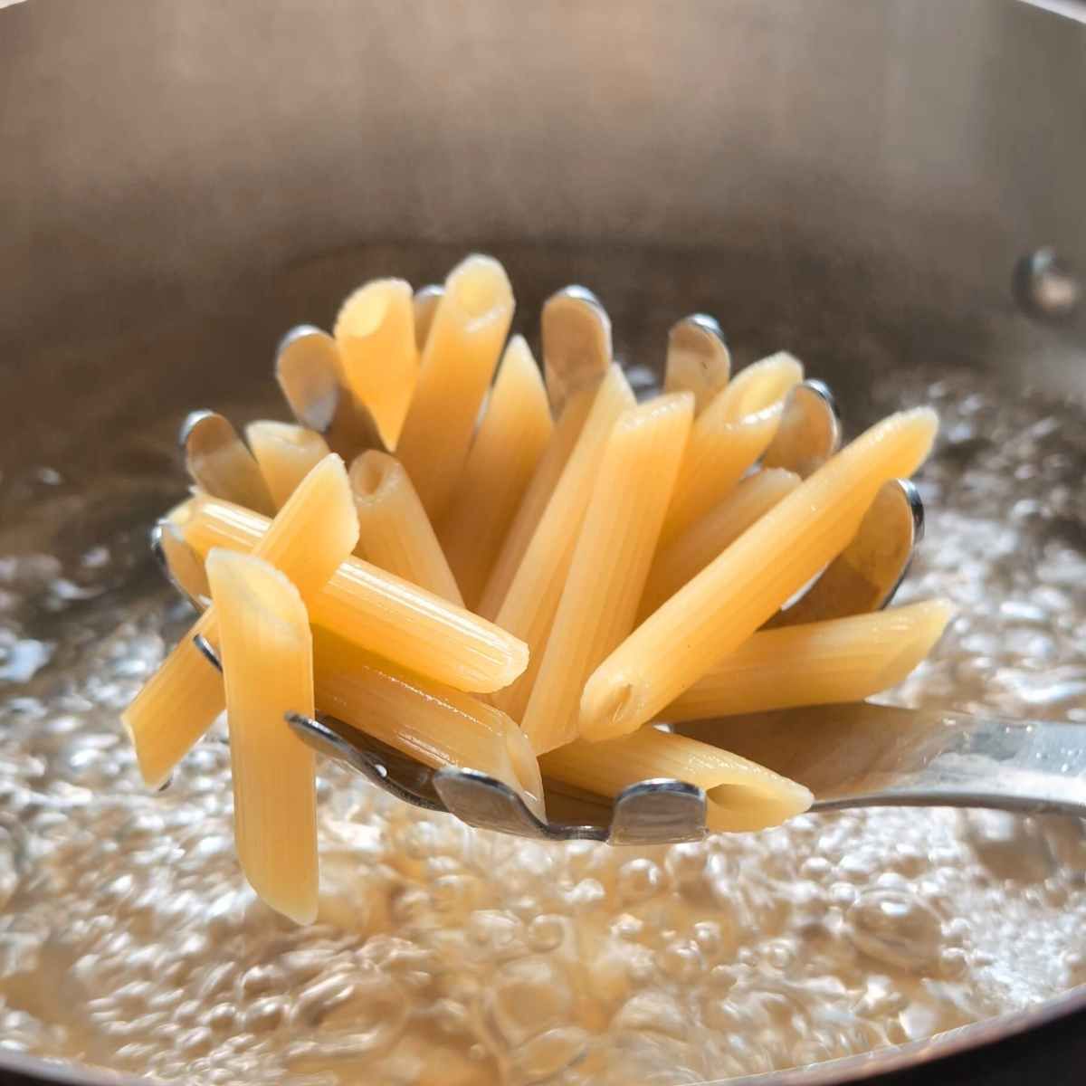 penne pasta being cooked in a pot of water ready for mozzarella sauce.