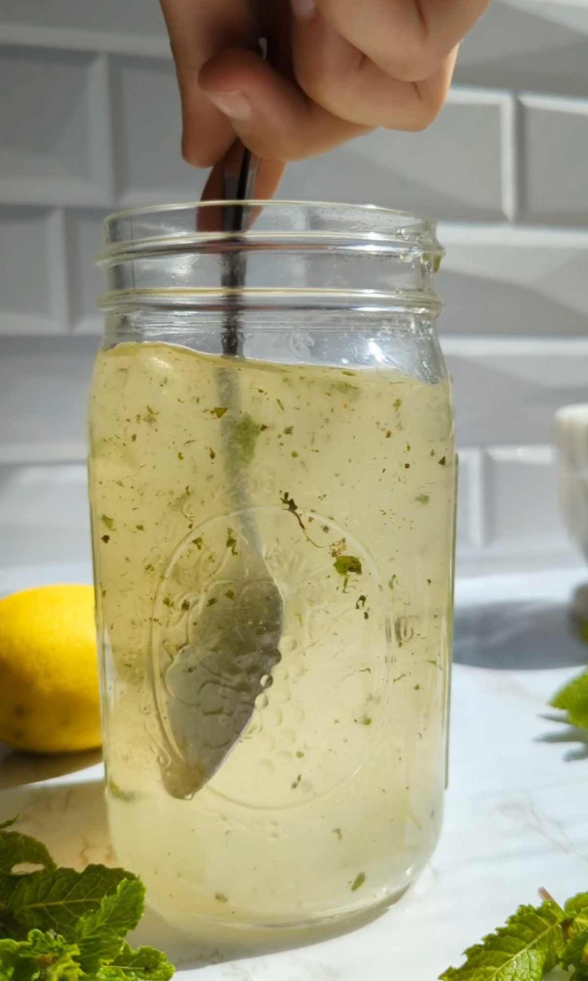 fresh muddled mint leaves being stirred into homemade lemonade.