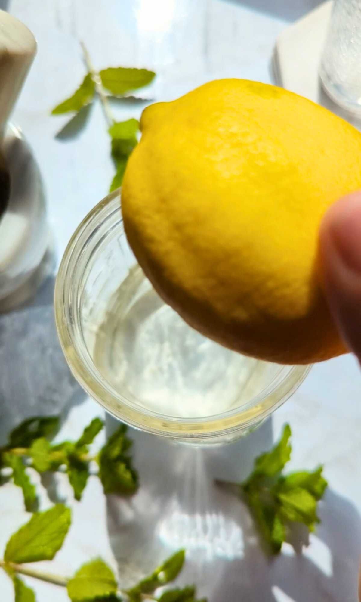 fresh lemons bring juiced into a mason jar to make homemade lemonade.