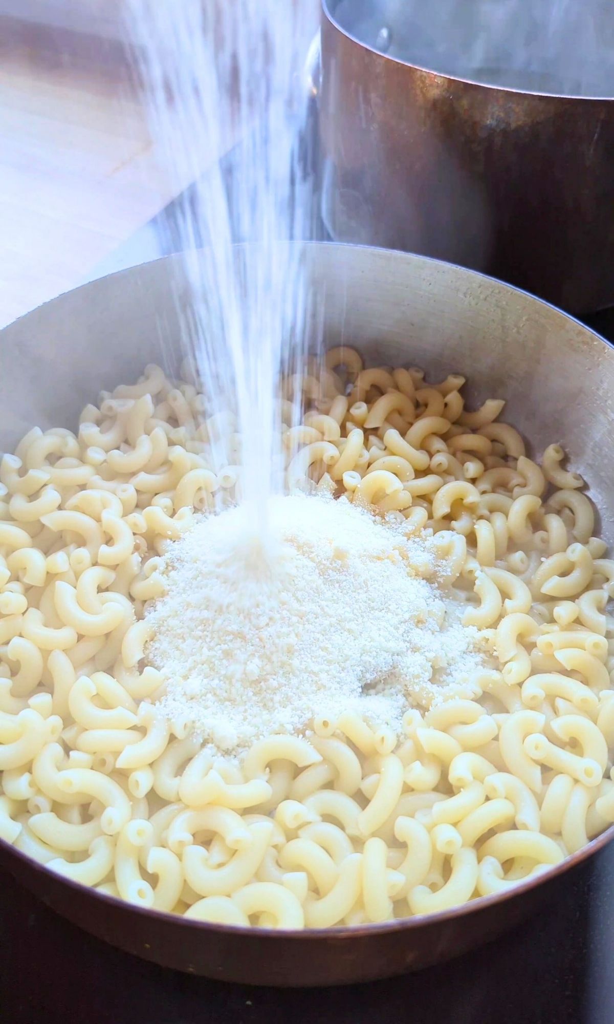 parmesan cheese sprinkled in a pan over cooked macaroni noodles and butter to make a thick sauce.