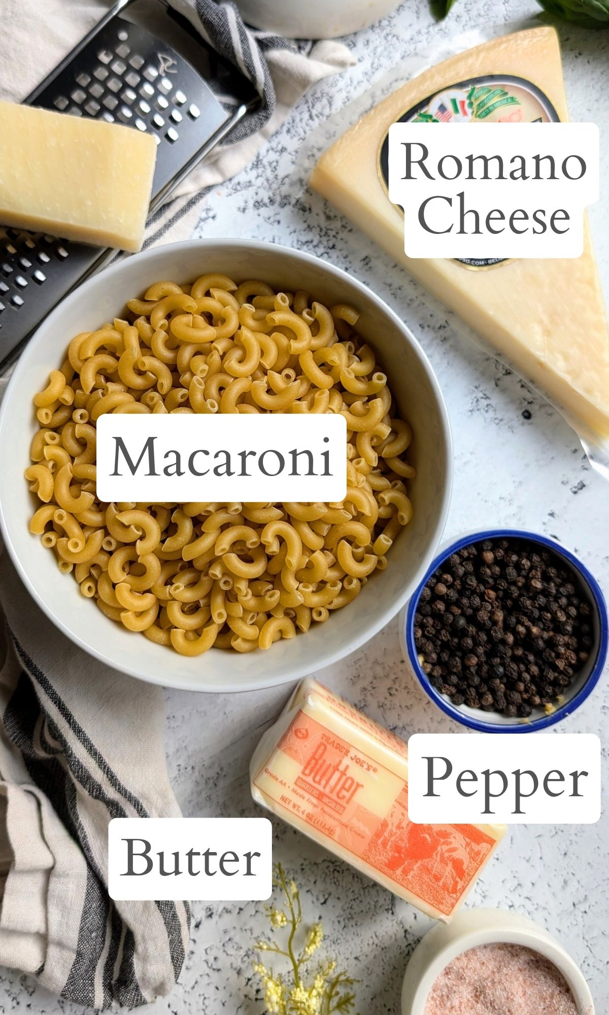 ingredients for cacio e pepe mac and cheese with macaroni noodles black pepper pecarino romano cheese and butter.