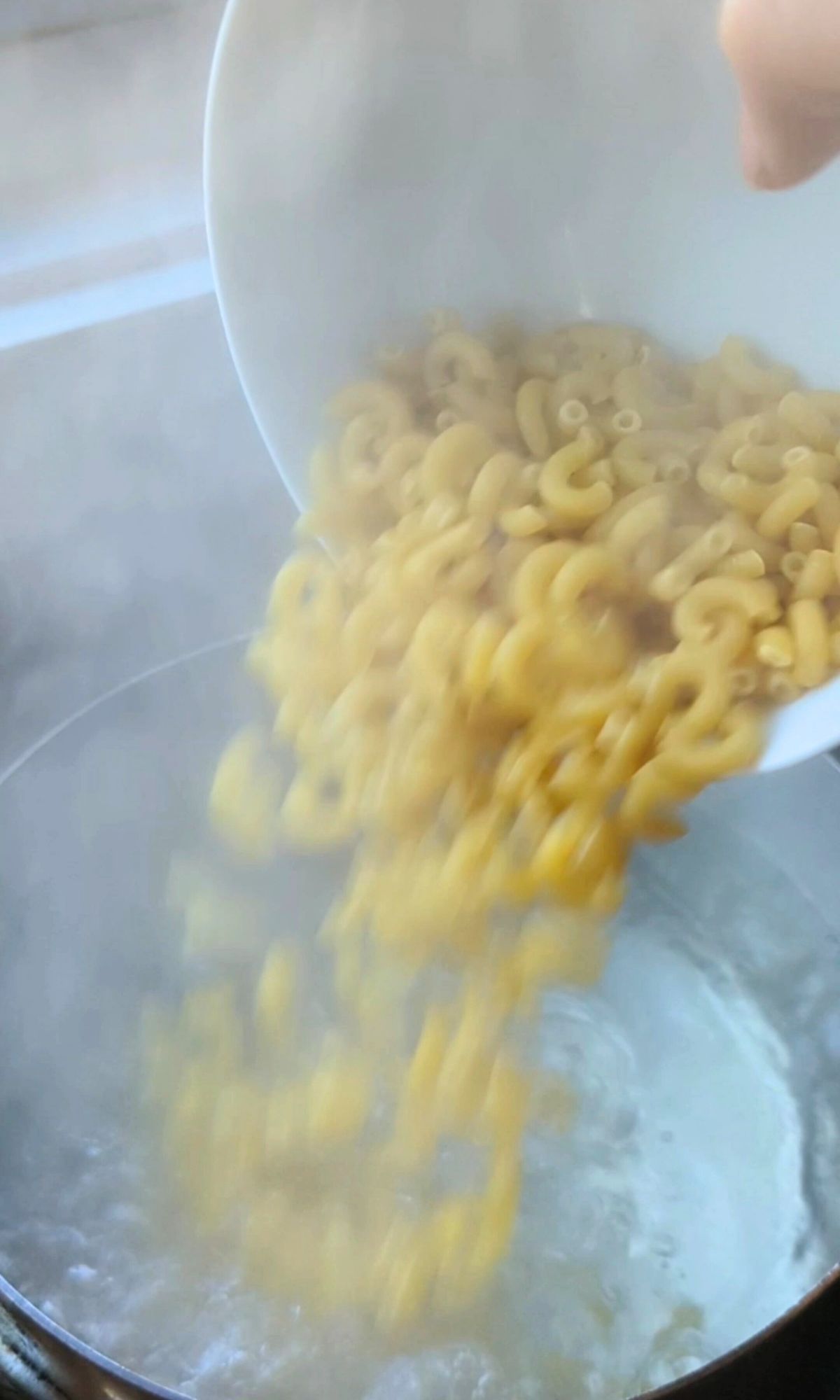 macaroni noodles being added to boiling water to cook the pasta for cacio e pepe.