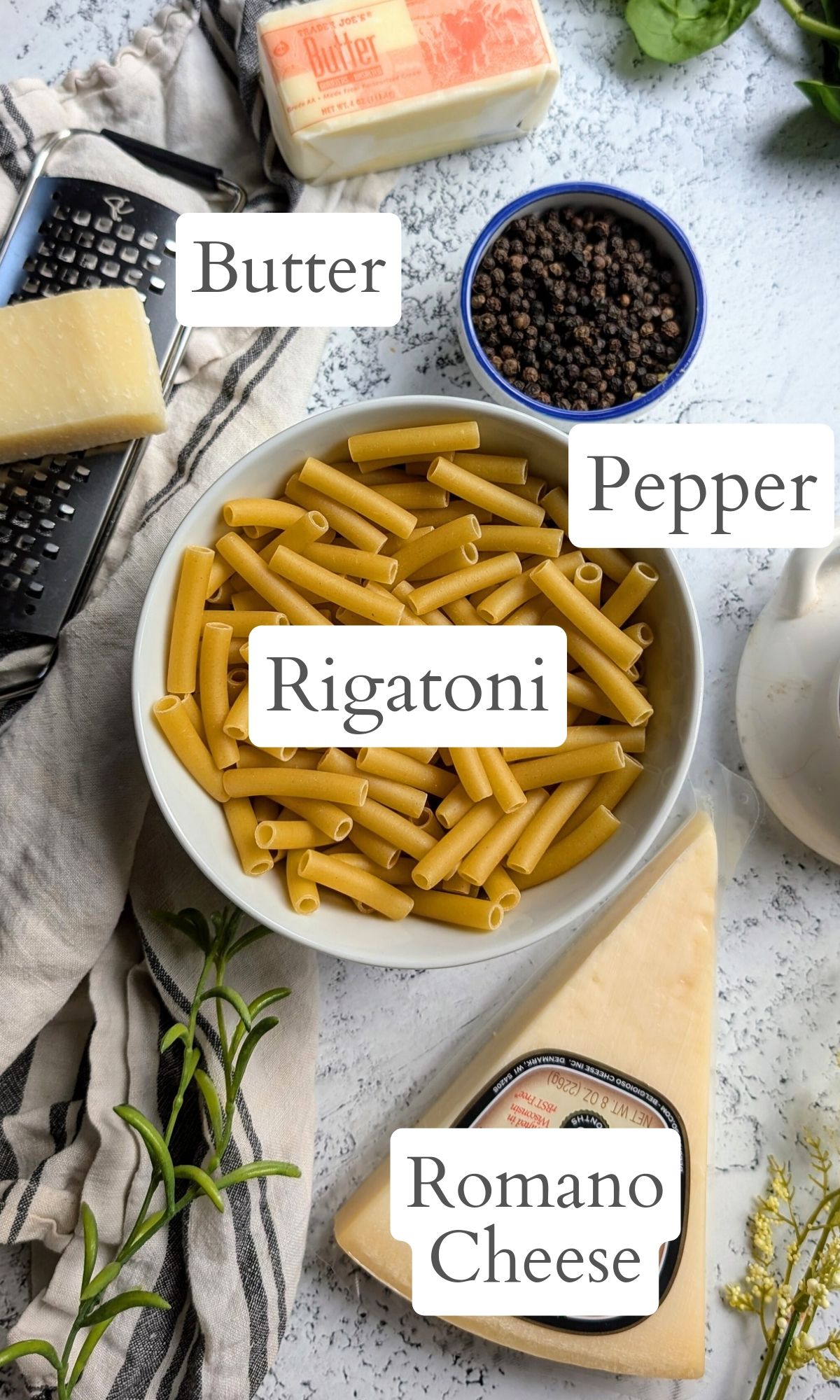 ingredients for cacio e pepe with rigatoni noodles, black pepper, romano cheese, and butter.