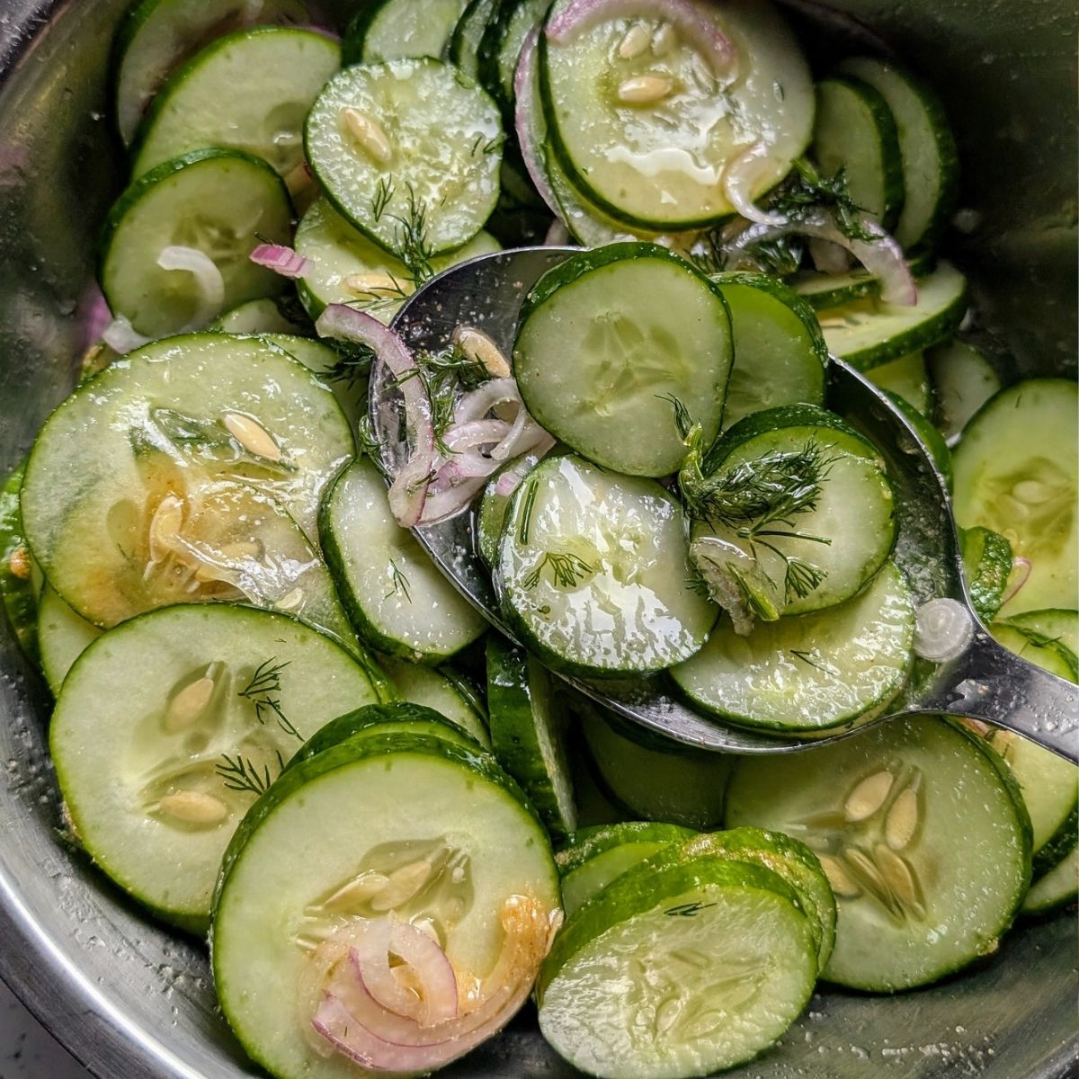 a large bowl of mixed cucumber salad with red onions in a rice wine dressing.