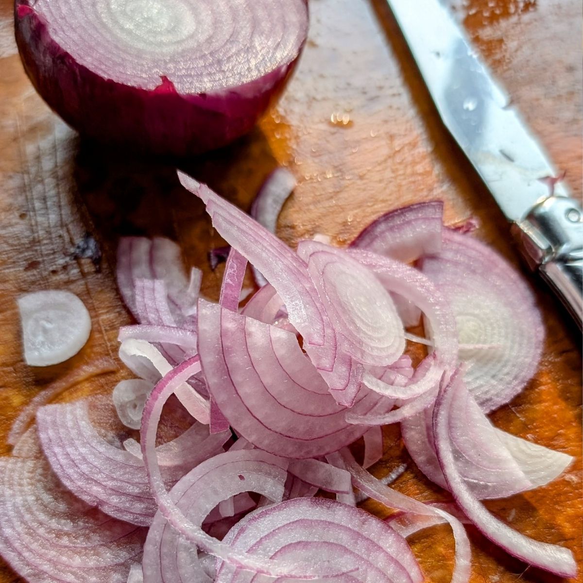 thinly sliced red onions on a cutting board.