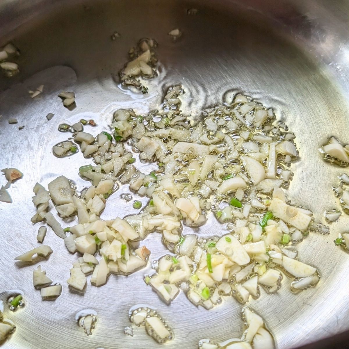 a large soup pot with olive oil and garlic browning at the bottom for soup.