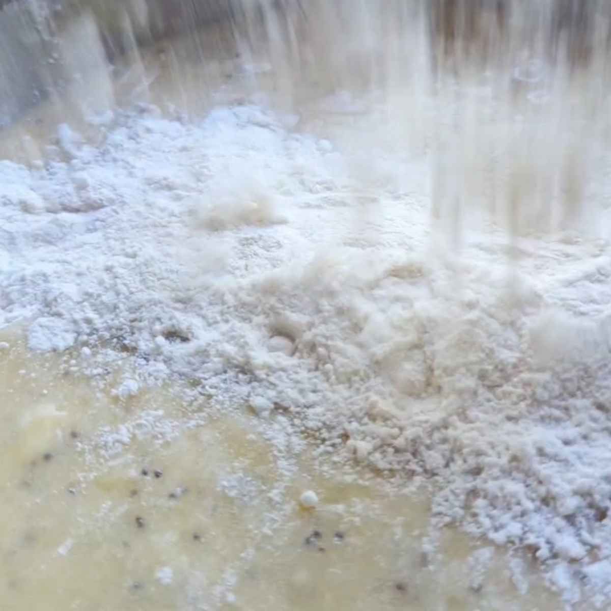 dry ingredients being mixed into wet ingredients for banana bread, a light, fluffy, and moist recipe.