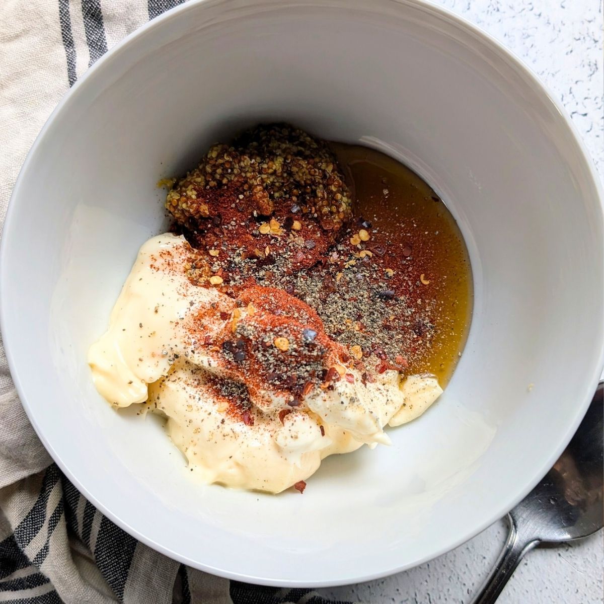 a bowl of mayonnaise, honey, dijon mustard, paprika, chili flakes, and black pepper.