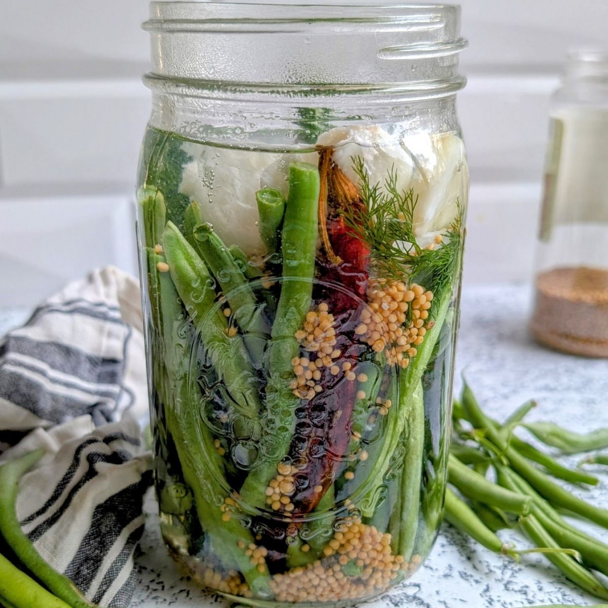 a mason jar with pickled beans and dill and garlic for bloddy caesar drinks.