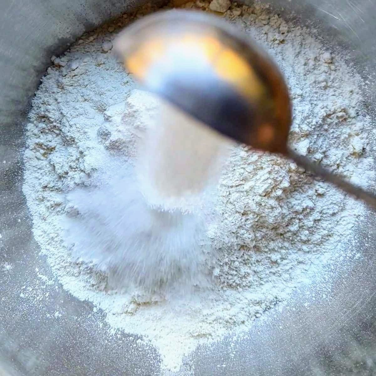 a bowl with baking powder sugar salt and flour, the dry ingredients for banana bread.