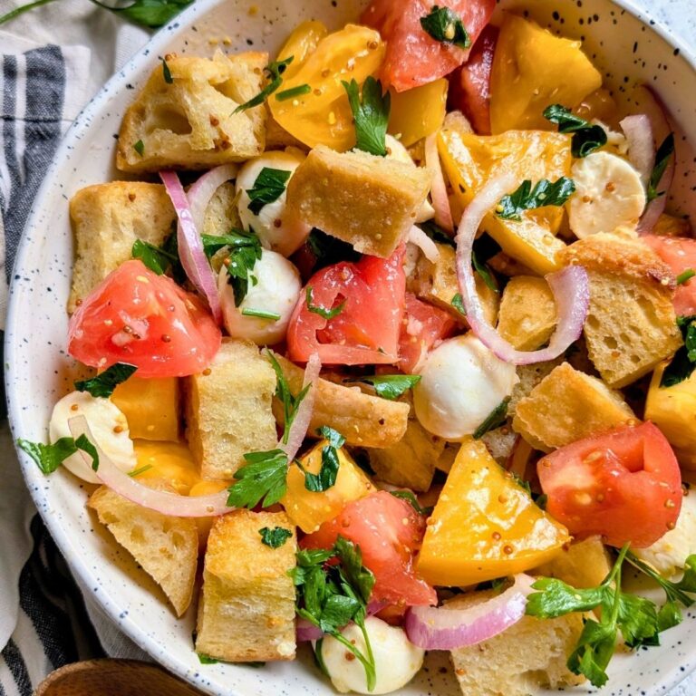 fresh panzanella salad with mozzarella and sourdough bread in a bowl with red onions and a homemade garlic vinaigrette.