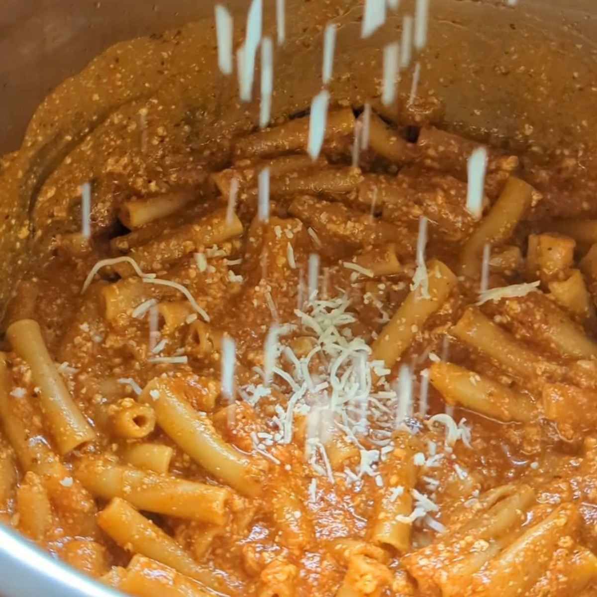 cooked pasta in the instant pot with a sprinkle of parmesan cheese in the pot.