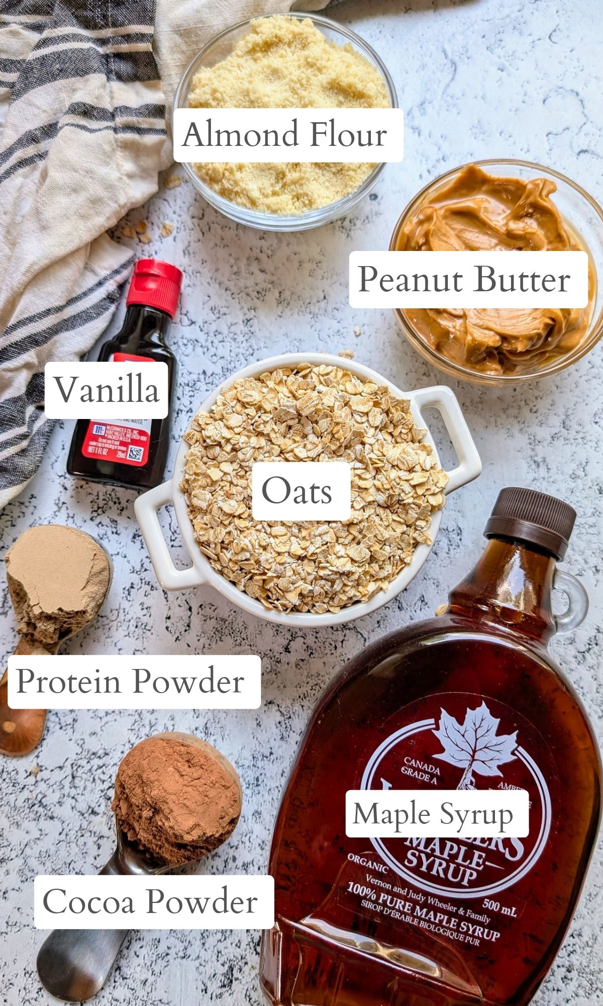 ingredients for chocolate energy bites with oats, vanilla, maple syrup, peanut butter, protein powder, and cocoa or cacao.