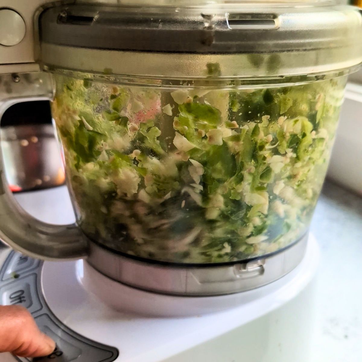 jalapeno hot sauce in a food processor being pulsed for a chunky sauce.