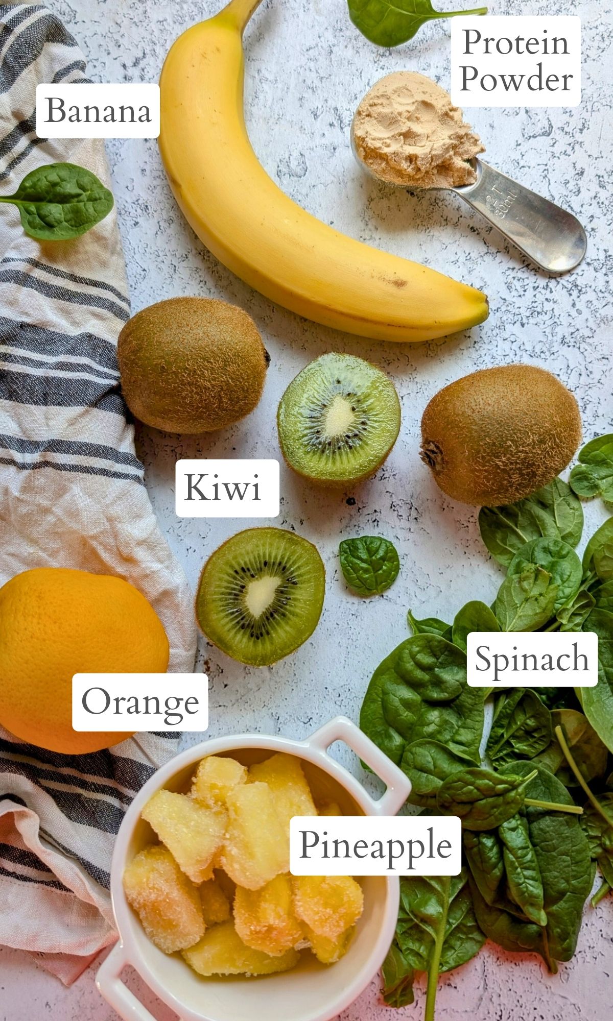 kiwi smoothie ingredients like fresh freen kiwi, bananas, oranges, pineapple, and spinach.