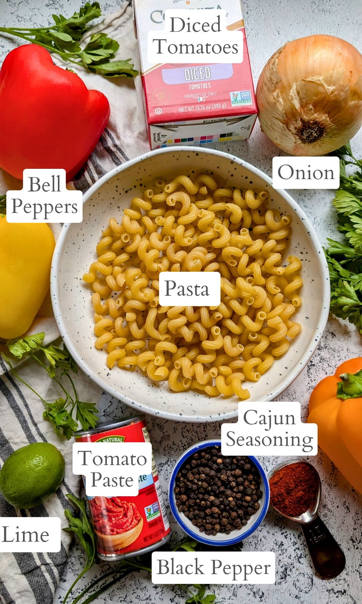 vegetarian cajun pasta recipe ingredients like pasta, bell peppers, onions, cajun seasoning, tomatoes and tomato paste and fresh herbs.