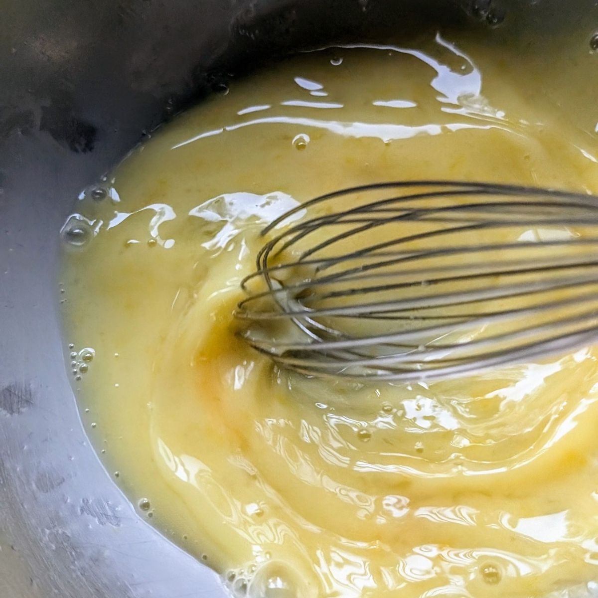 a mixing bowl with lemons and eggs whisked together to make avgolemono broth.