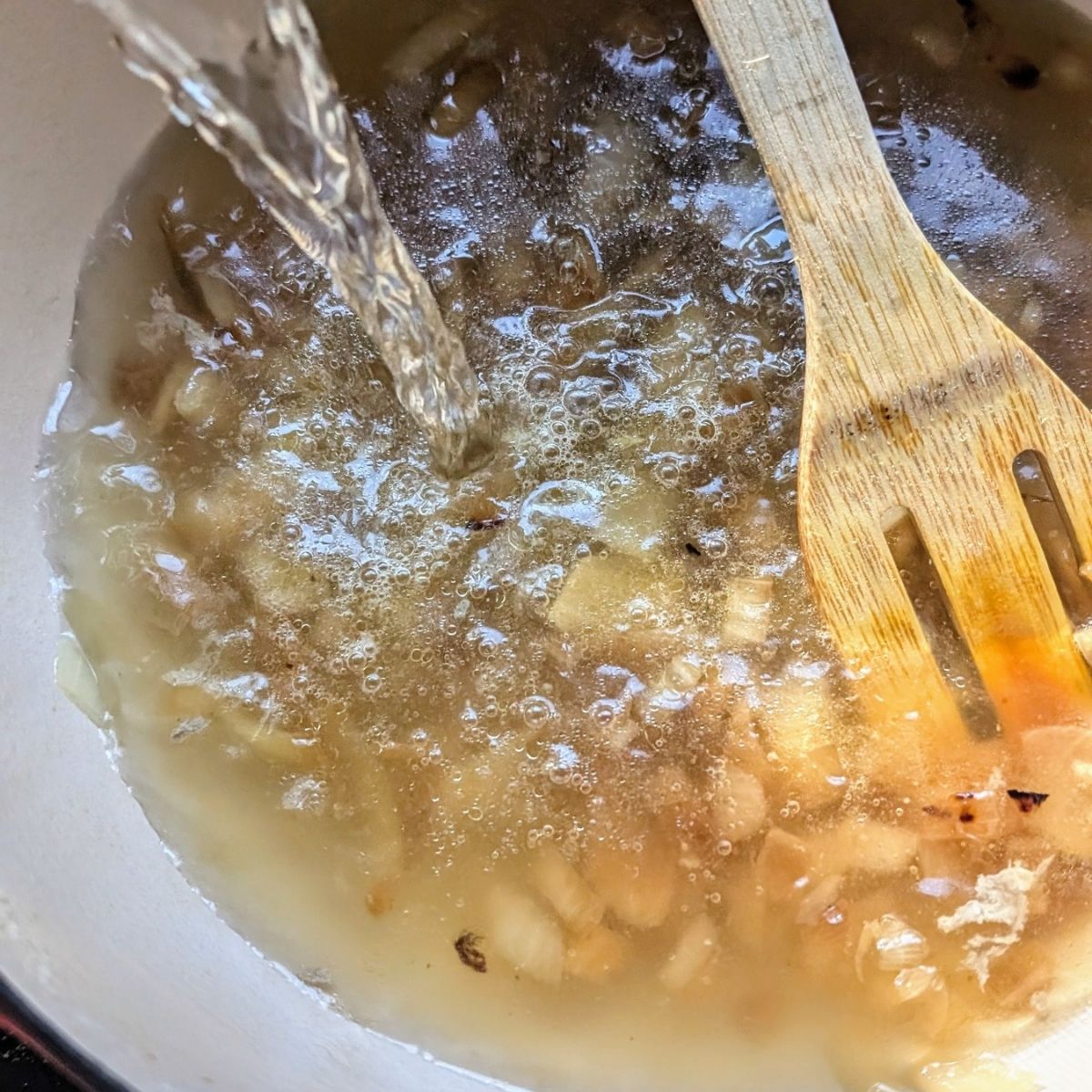 chicken broth and shredded cooked chicken in a pot for homemade greek chicken soup.