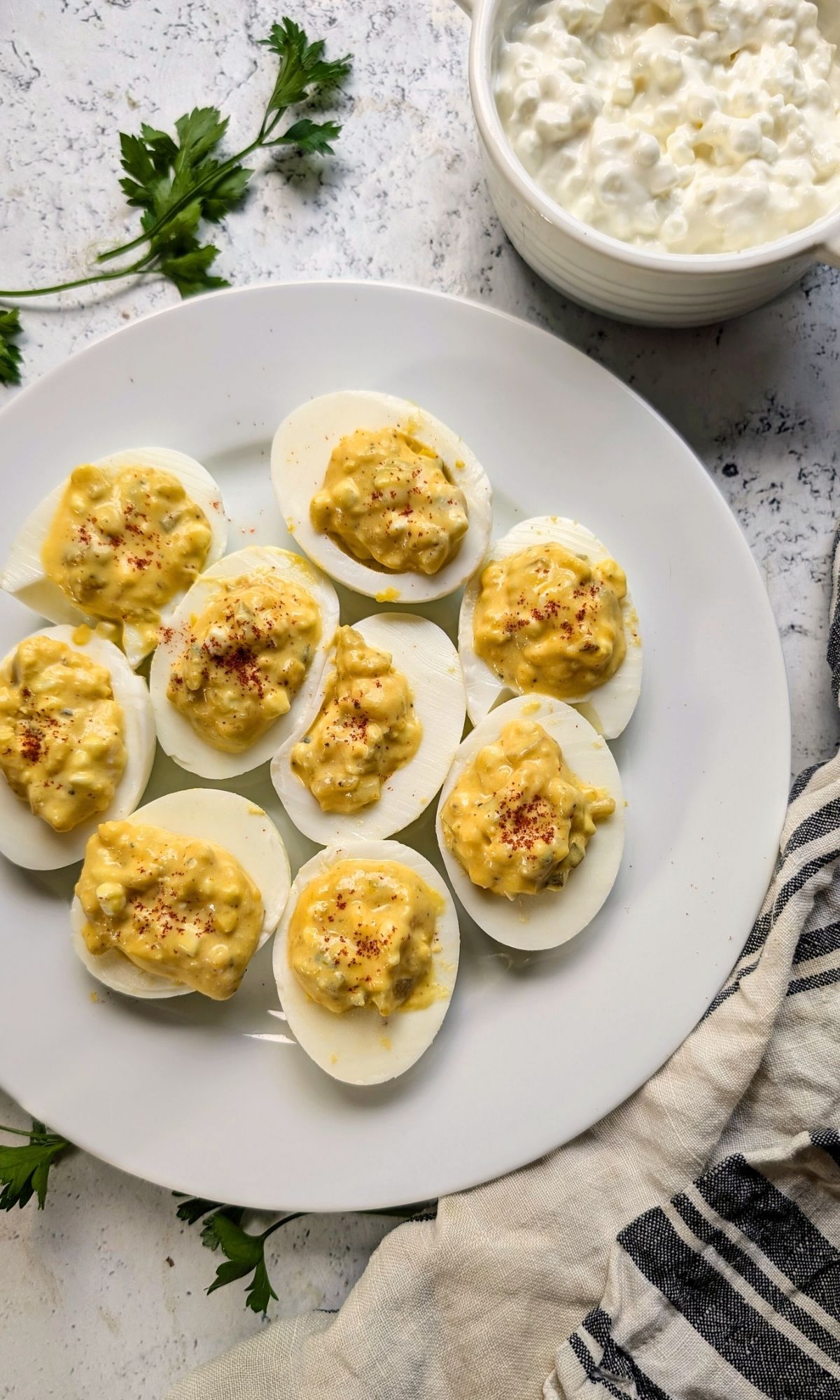 deviled eggs with cottage cheese on a plate with fresh herbs ready to serve as a high protein side dish for a party.