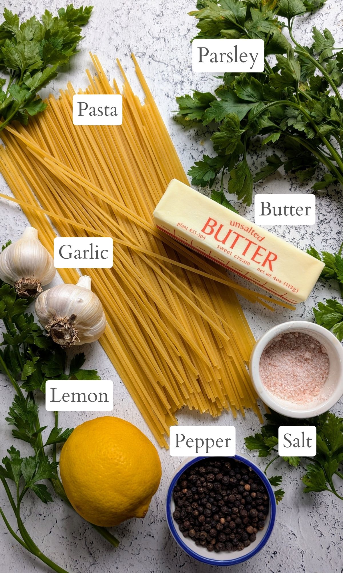 ingredients for fresh parsley pasta like noodles, garlic, butter, salt, pepper, and lemon juice.