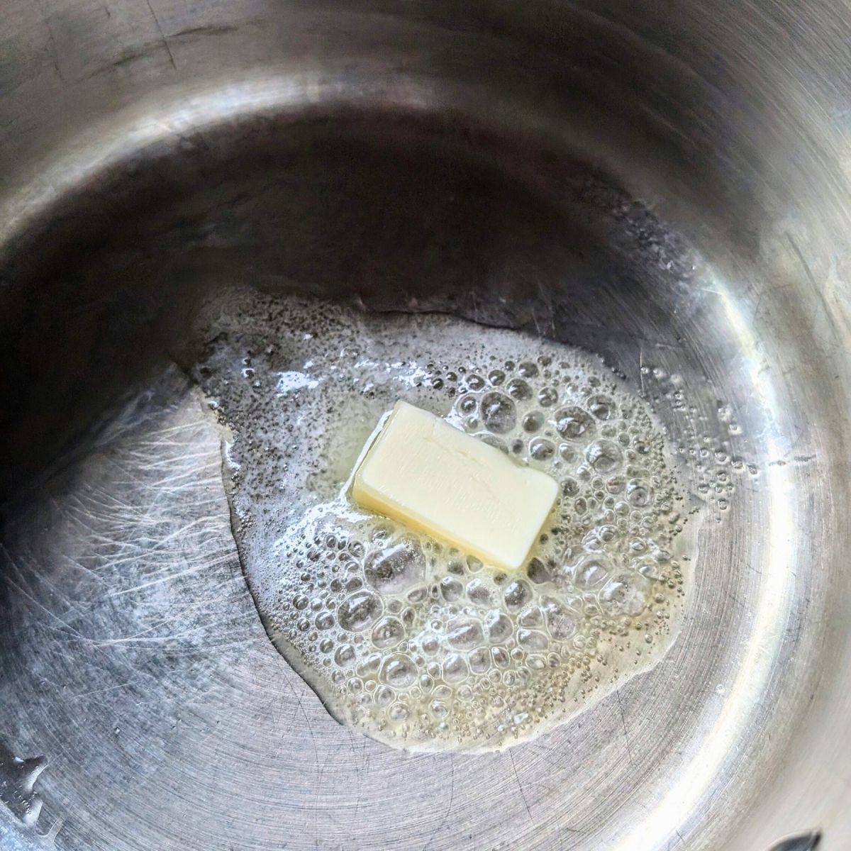 melted butter being heated in a pot to make a tasty homemade sauce with fresh herbs.